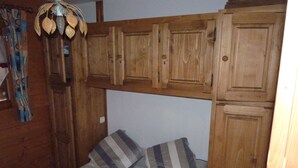 Een slaapkamer met een bed, een houten garderobe en een hanglamp.