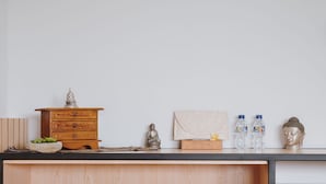 A wooden desk with a statue, a Buddha head, and two water bottles. - Borobudur Bed & Breakfast - Hostel (Mungkid)