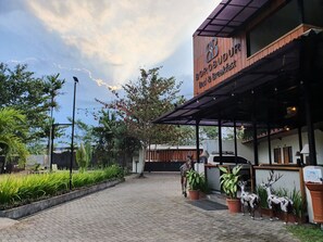 A Borobudur restaurant with a covered outdoor seating area, potted plants, and a paved entrance. - Borobudur Bed & Breakfast - Hostel (Mungkid)