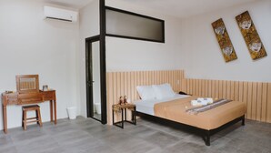 A modern bedroom with a bed, wooden headboard, a desk with a chair, and a small table with decorative items. - Borobudur Bed & Breakfast - Hostel (Mungkid)