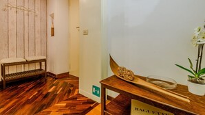Un banco de madera con una toalla, una mesa de madera con un cuenco y palillos, y un marco de fotos colgado en la pared.