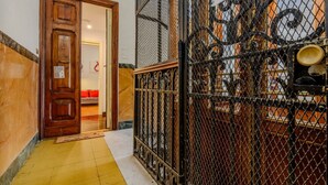 Una porta in legno che dà su una stanza con un cuscino rosso, un pavimento a piastrelle gialle e un recinto metallico con decorazioni.