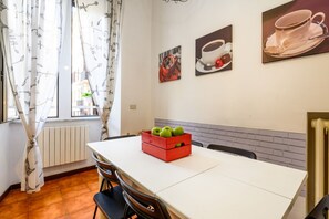 A dining area with a table, chairs, a radiator, and artwork on the wall.