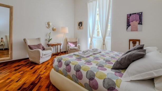 Una camera da letto con un letto grande, due sedie, un tavolino e uno specchio.