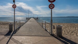 Une promenade en bord de mer dotée d’une rambarde, de poubelles et de panneaux de signalisation.