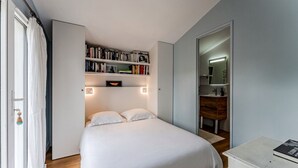 Une chambre à coucher avec un lit, une bibliothèque, une commode et un miroir.
