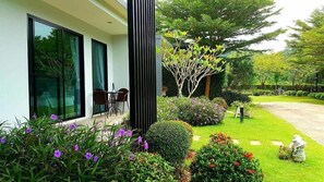 A modern house with a patio, a dining area, and a well-maintained garden. - The Focus Khaoyai Resort (Pak Chong)
