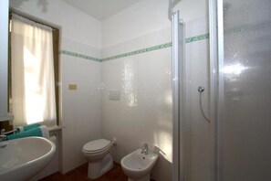 Une salle de bain équipée de toilettes, d’un bidet et d’une douche.