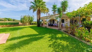 Une maison dotée d’un patio, de palmiers et d’une pelouse bien entretenue.