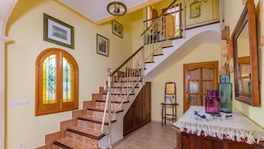 Un escalier avec une rampe en bois et un mur blanc orné d’un tableau encadré.