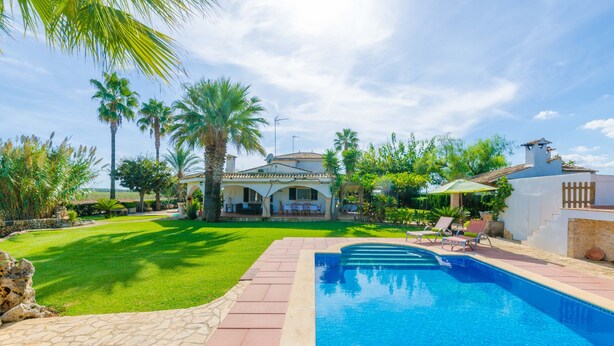 Une piscine avec un chemin de pierre menant à une maison dotée d’une terrasse.