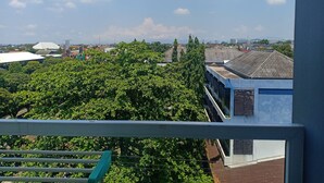 A view from a balcony overlooking a cityscape with buildings, trees, and a clear sky. - AGV Apartment Yogyakarta (Depok)