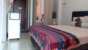 A bedroom with a bed, a wardrobe, a desk, and a water dispenser. - AGV Apartment Yogyakarta (Depok)