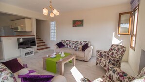 A living room with a sofa, armchair, and a coffee table. There is a television and a small cabinet. - 5 Bedrooms, heated pool, pool table, table tennis, bbq & wifi. (Mugla)