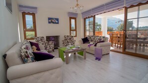 A spacious living room with a sofa, chairs, a coffee table, and a view of the outdoors. - 5 Bedrooms, heated pool, pool table, table tennis, bbq & wifi. (Mugla)