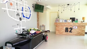 Un comptoir d’accueil portant l’inscription « R2 », avec un revêtement en bois, une carte accrochée au mur et une voiture jouet avec un panneau.