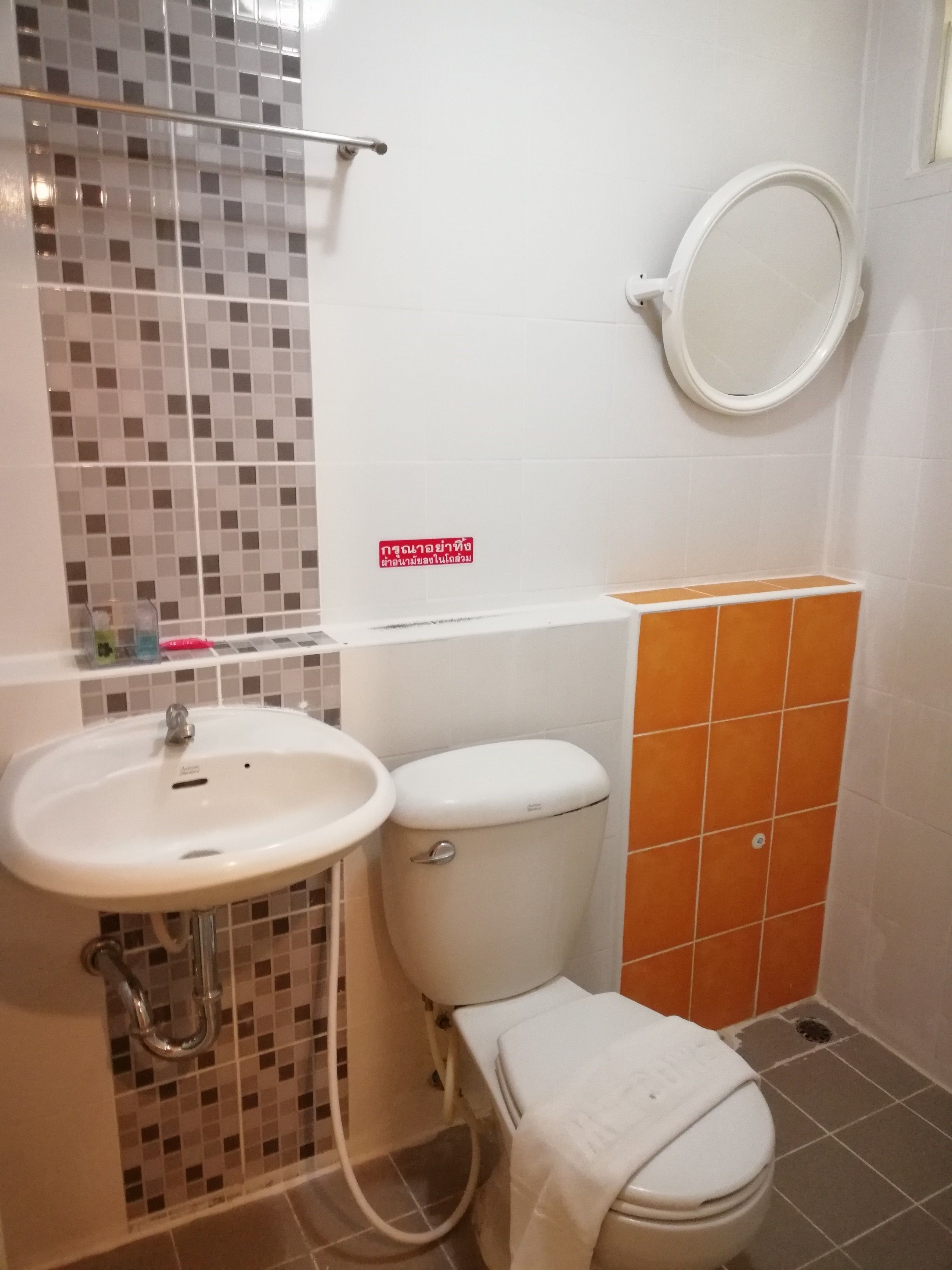A bathroom with a white sink, toilet, and a mirror on the wall.
