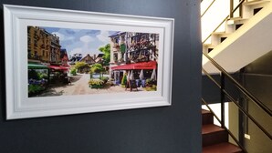 Un tableau encadré représentant une scène de rue avec des bâtiments et des boutiques.