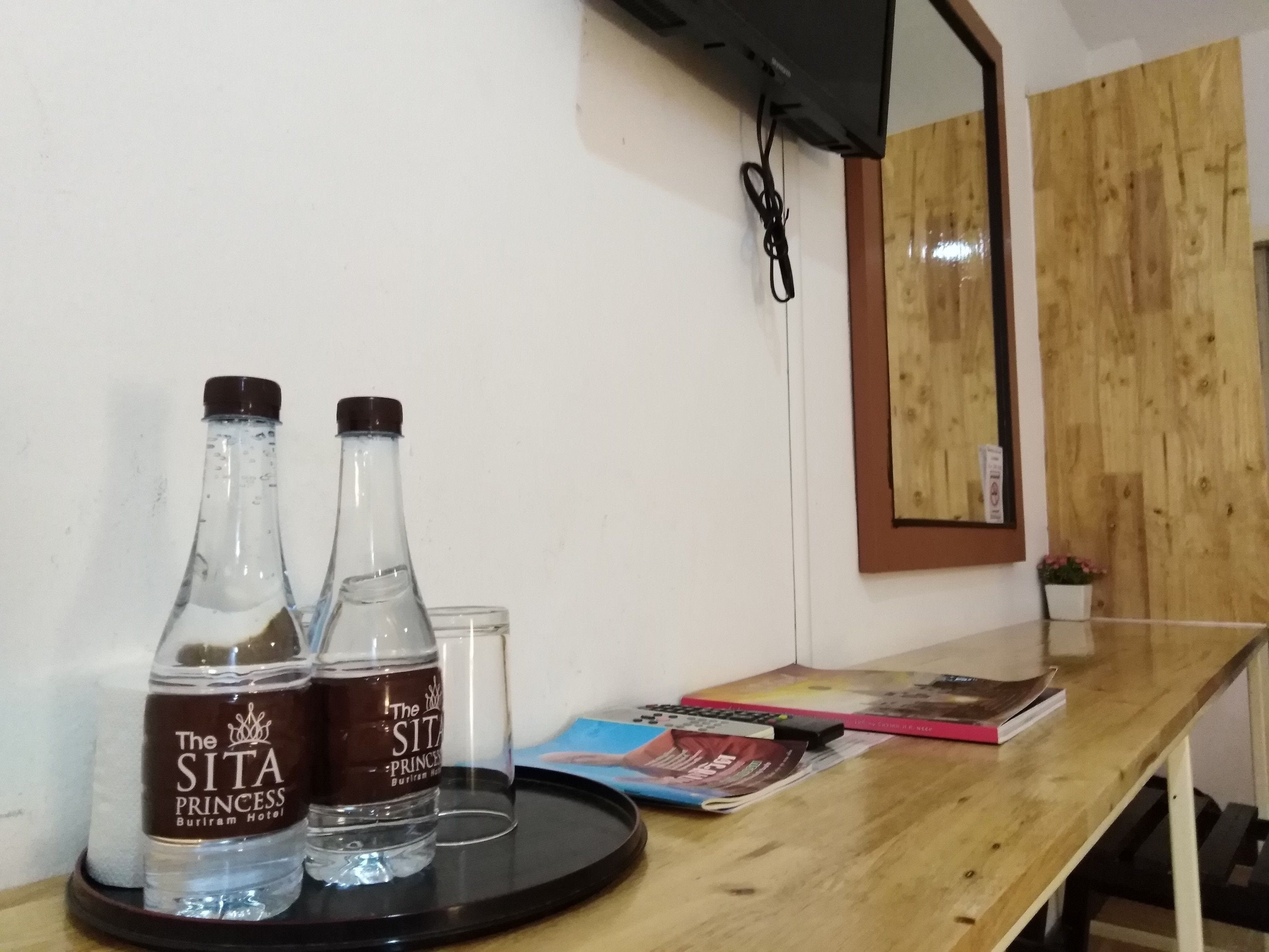 Un comptoir d’accueil en bois, avec deux bouteilles d’eau, un verre et quelques livres.