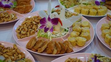 Una mesa con diversos platos, incluyendo alimentos fritos, nueces de cajú y un centro de mesa decorativo con flores.