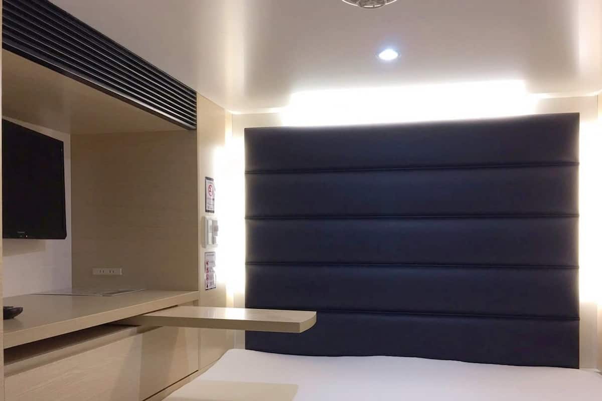 A modern bedroom with a bed, bedside table, and a mounted TV.