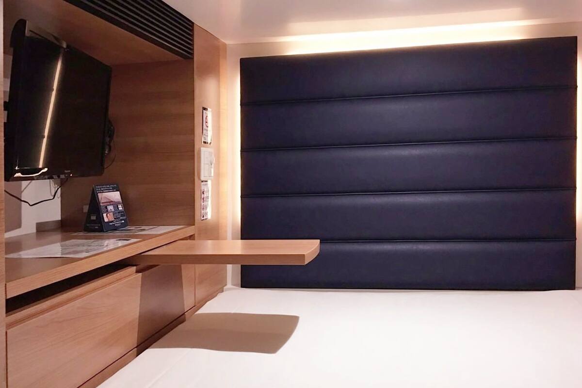 A modern bedroom with a bed, wooden bedside tables, a flat-screen TV, and a dark headboard.