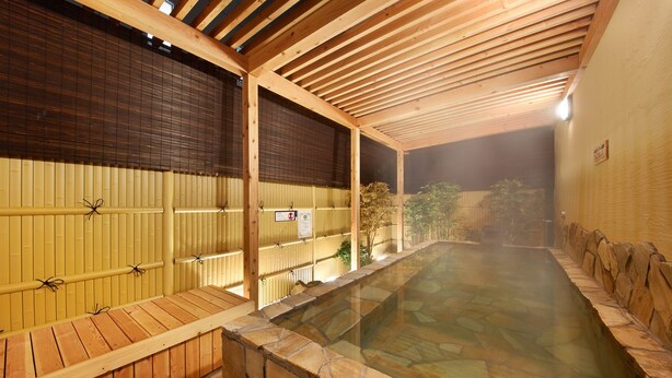 A traditional Japanese onsen with wooden benches and a stone bath area.