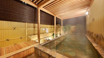 Relax in a serene stone-lined pool surrounded by wooden benches and a low wall.