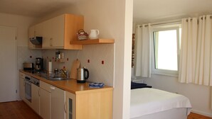 A compact room with a kitchenette, a bed, and a window with curtains. - Idyllic "witches house" directly on the lake with private jetty (Hohenferchesar)