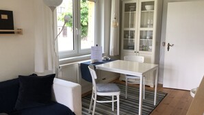A compact living space with a white table and chair, a black sofa, a radiator, and a cabinet with glass doors. - Idyllic "witches house" directly on the lake with private jetty (Hohenferchesar)
