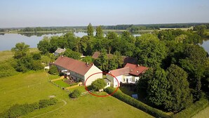 A large house with a red roof surrounded by lush greenery and a lake. - Idyllic "witches house" directly on the lake with private jetty (Hohenferchesar)