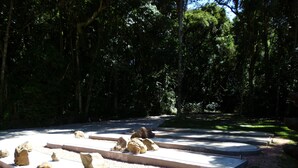 A circular stone structure surrounded by gravel, with a paved path leading to it.