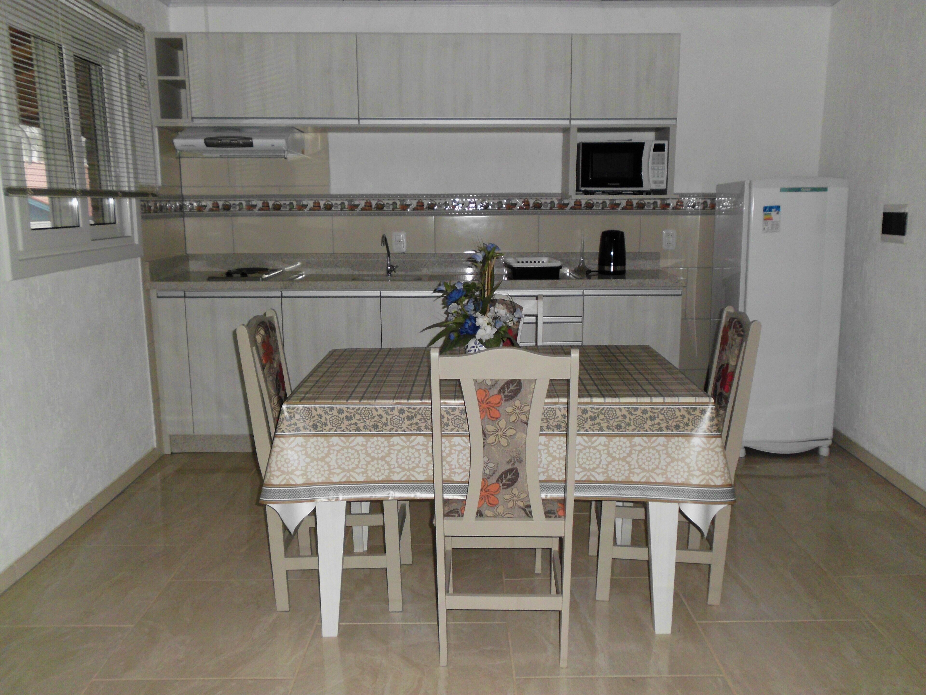 A small kitchen with a dining table, chairs, a microwave, and a refrigerator.