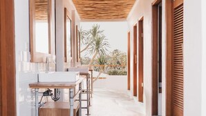 A corridor with hexagonal tiled flooring, wooden benches, and a wooden ceiling. - Kos One Hostel (Canggu)