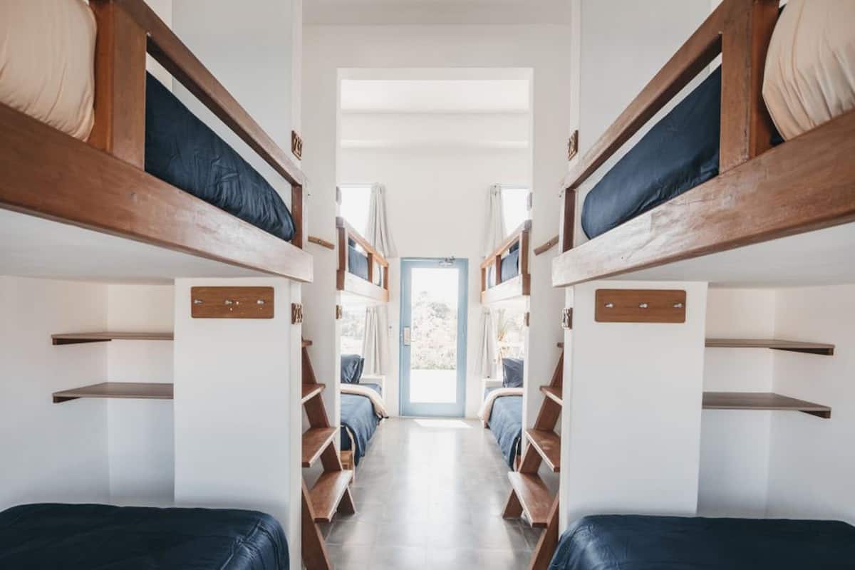 Un pasillo estrecho con literas a ambos lados, que conduce a una puerta con vistas al exterior.