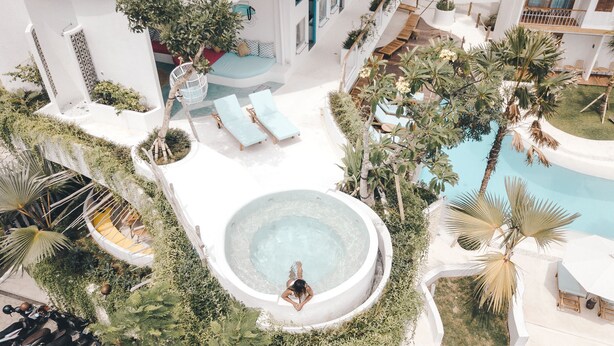 A rooftop pool area with lounge chairs, a hot tub, and surrounding greenery. - Kos One Hostel (Canggu)