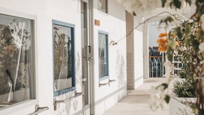 A modern building with white exterior walls, blue-framed windows, and a wooden ceiling. - Kos One Hostel (Canggu)