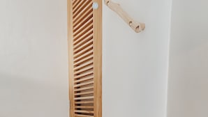 A corner of a room with a wooden shelf unit against a white wall. - Kos One Hostel (Canggu)