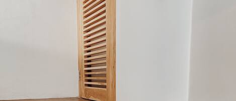 Un rincón de una habitación con una estantería de madera adosada a una pared blanca.