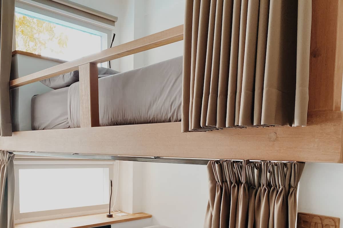 Habitación con literas, ventana, cortinas y cabecero de madera.