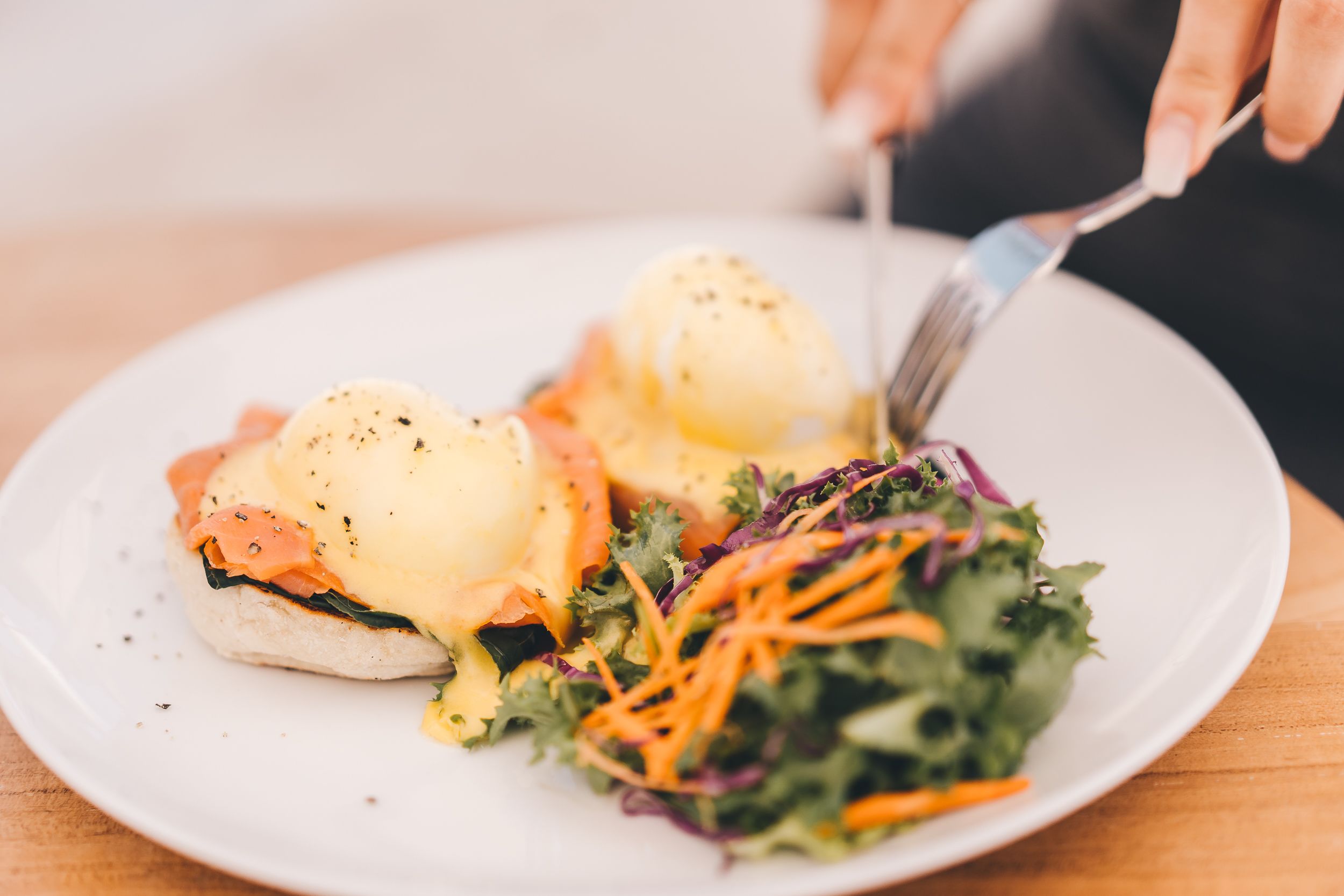 A plate with eggs benedict, smoked salmon, and a side salad.