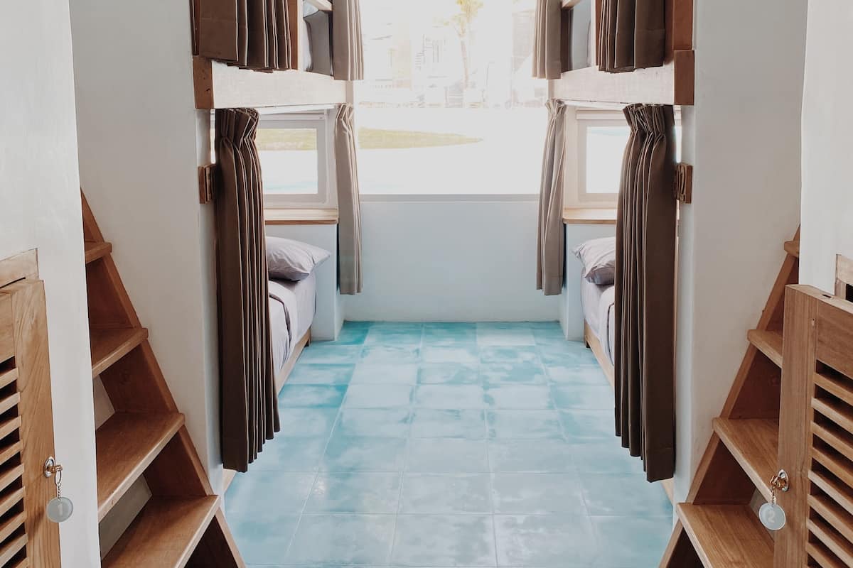 Un dormitorio con literas, una ventana con cortinas y un suelo de baldosas azules.
