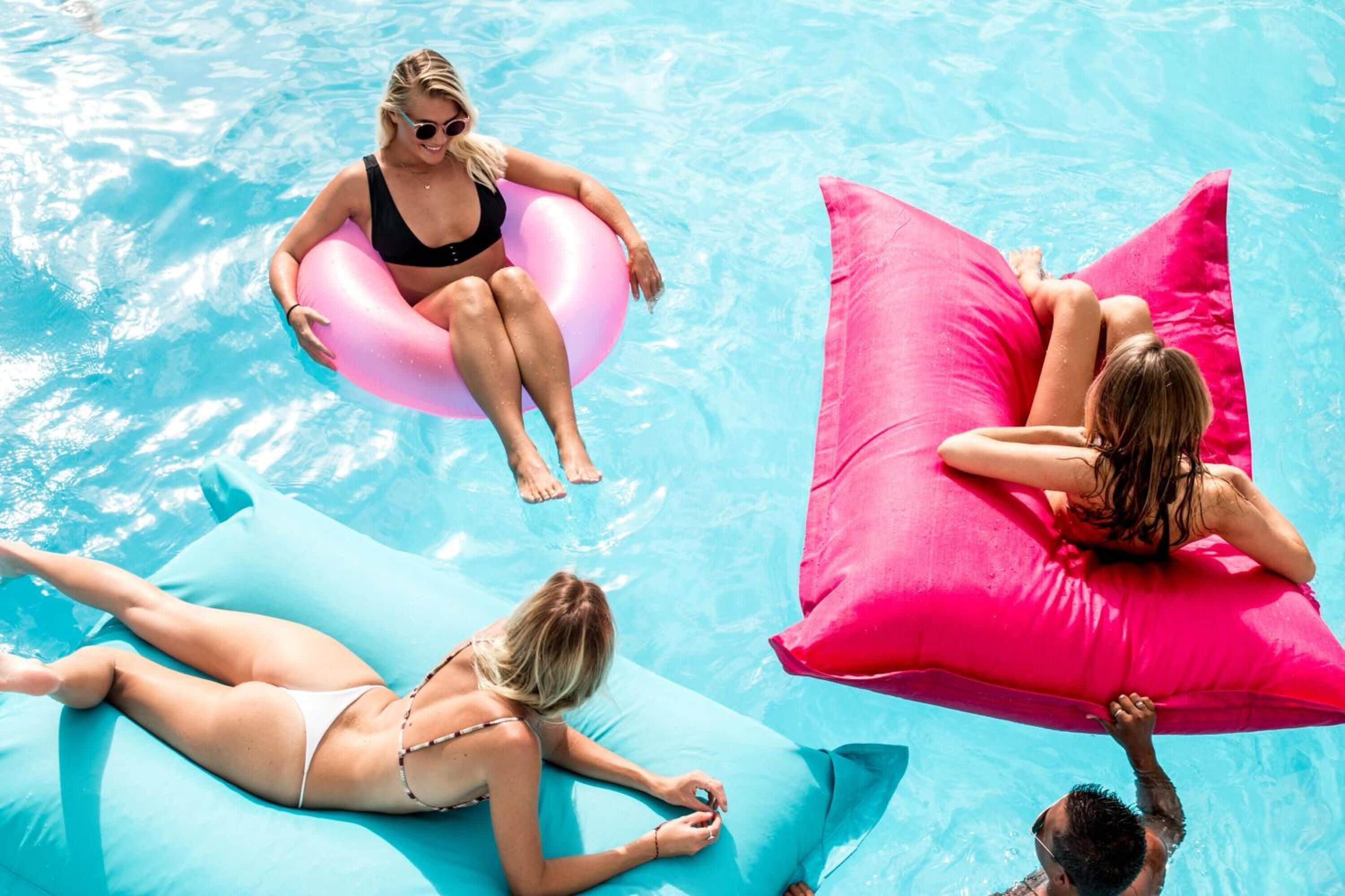 A swimming pool with people relaxing on inflatable floats.