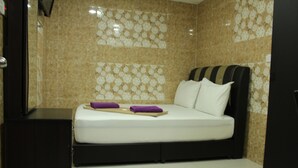 Una habitación de hotel con una cama, un escritorio pequeño y un armario.