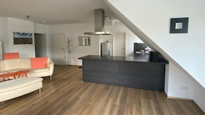 A modern living room with a sofa, a coffee table, and a kitchen area with a dark countertop.