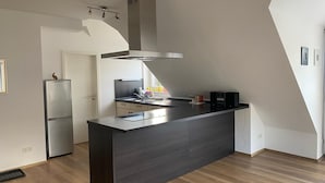 A modern kitchen with a central island, a built-in oven, and a stainless steel refrigerator.