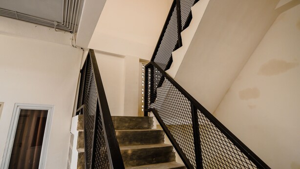 A staircase with a black metal railing and a white wall. - OYO 183 The Pipe House (Palembang)