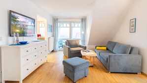 A modern living room with a sofa, ottoman, and a small table. - Family-friendly vacation apartment Seeschwalbe in Koserow - Holiday apartment (Koserow)
