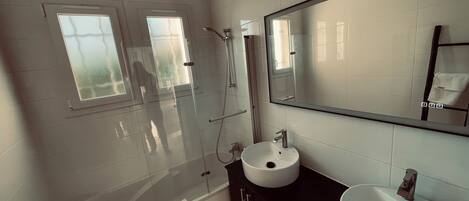 A modern bathroom with a glass-enclosed shower, a white bathtub, and a black vanity with a white sink.