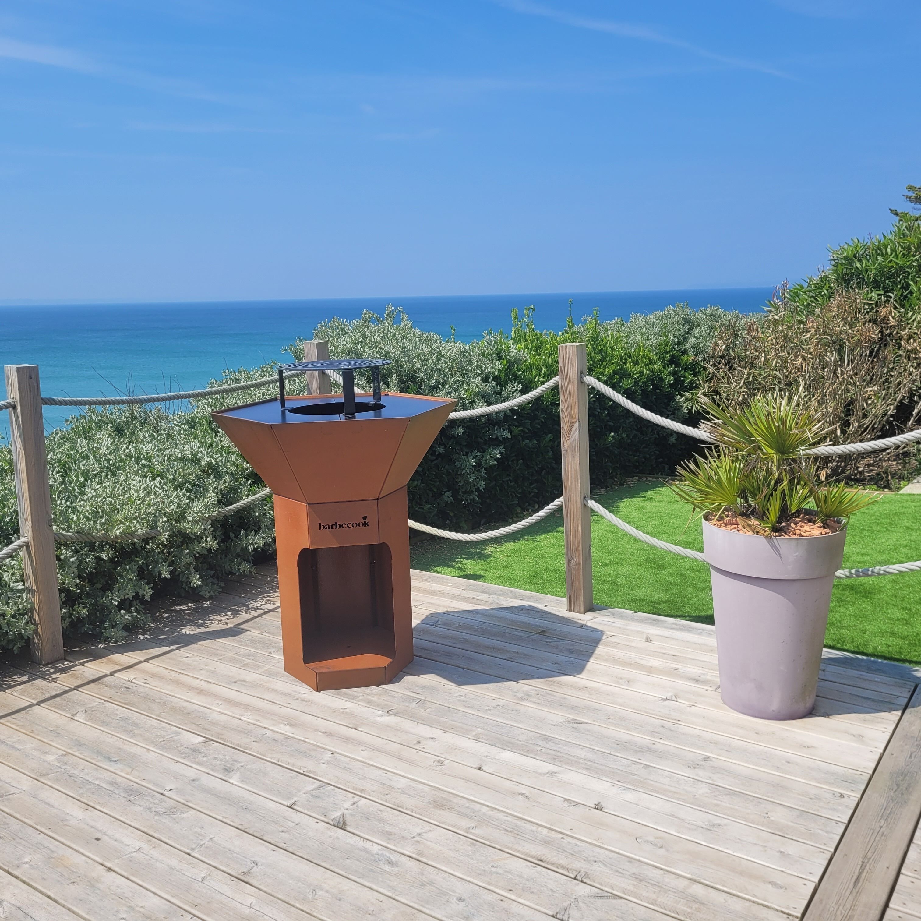 Un barbecue installé sur une terrasse en bois, avec vue sur l’océan.